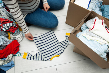 the pregnant woman is sorting baby clothes