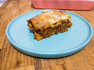 Homemade fresh lasagna on a plate on a wooden surface