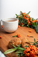 View of Melomakarono, Greek Christmas traditional dessert , with a cup of tea surrounded by sea ​​buckthorn, on wood.   Selective focus