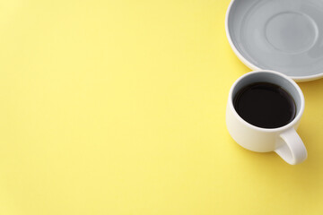 Gray cup of coffee on yellow background with copy space