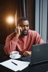 Businessman Using Phone Working On Laptop In Coffee Shop