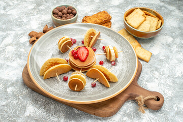 Top view of homemade pancakes and biscuits on wooden cutting board on blue backgound