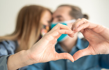 Fototapeta premium Young loving couple kissing and holding hands in shape of heart. Saint Valentines during Covid-19