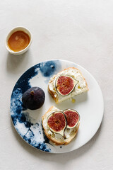 Two Sandwich with Ricotta and fresh Figs sprinkled honey on plate on grey concrete background. Simple healthy breakfast