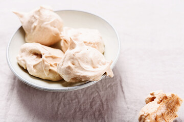 Homemade sweet meringue cookies on greige linen tablecloth. Delicious and light dessert. Selective focus