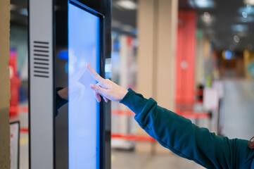 Faceless woman in medical mask uses electronic information board in a public place