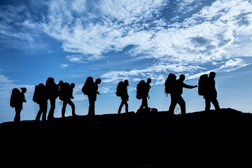 Fototapeta na wymiar Silhouette of tourists on the blue sky background.