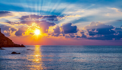 Calm sea and cloudy sky pierced with sun rays. Beautiful nature background.