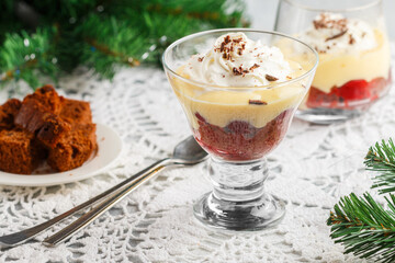 Dessert Black Forest of chocolate sponge cake or brownie with cherries, custard and whipped cream in a glass glass. Trifle. New Year. Christmas. A festive treat for gourmets. Selective focus - 399530042