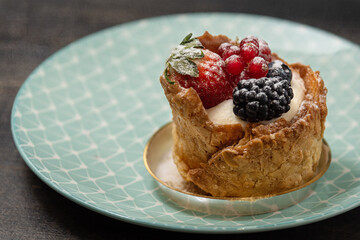 Dessert with custard cream and berries on blue plate. Side view, selective focus