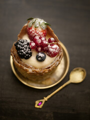 Dessert with custard cream and berries on golden plate with golden spoon. View from above,selective focus