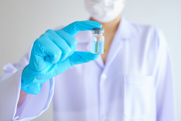 Female doctor or scientist in laboratory with stethoscope holding holds an injection syringe and COVID-19 or coronavirus vaccine. Healthcare And Medical concept.