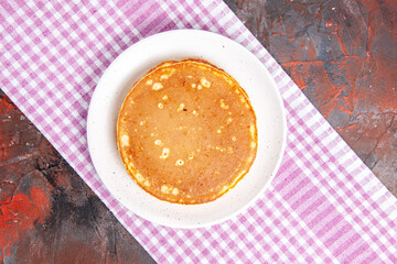 Overhead view of delicious pancakes on a pink stripped towel on mixed color background