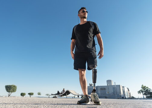 Young disabled man with prosthetic leg outdoors, low angle shoot.