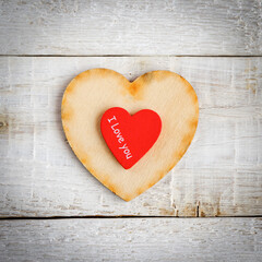 Two hearts with the text I love you on a wooden background