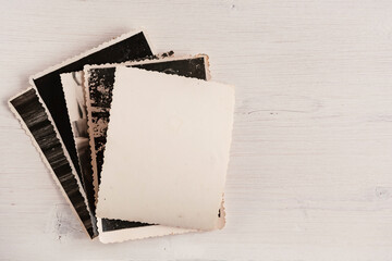 A stack of old photos with an empty reverse side on a wooden background. Vertical position