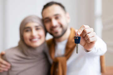 Joyful Muslim Couple Showing New House Key Standing Indoors