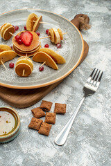 Buttermilk fruit pancakes on wooden cutting board with biscuits and honey on blue background