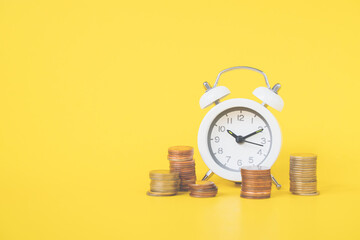 white analog clock white blurred stack of coins on vivid yellow background for business and  finance concept , time passing more cash value, growth value
