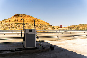 Old gas station along a desert empty road near yellow hills and blue clear sky
