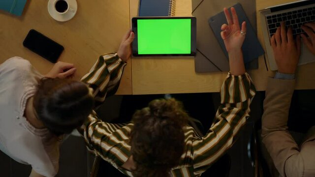 Woman showing project to colleagues on green screen device. Team using tablet.