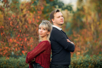 Fototapeta premium blonde girl in maroon sweater, brown-haired young man in blue sweater hug in the Park