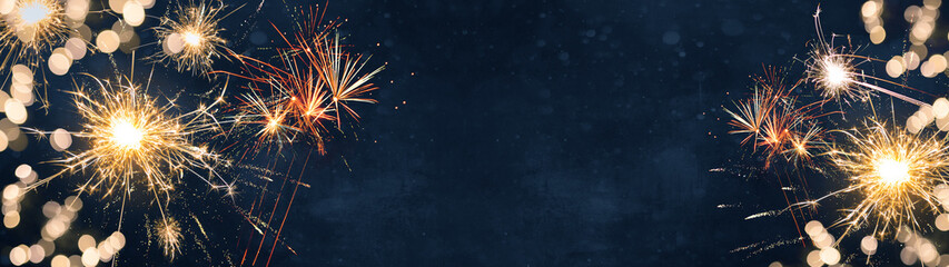 Silvester background banner panorama long- firework and sparklers on rustic dark blue night sky...