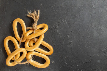 Ring-shaped cookies with a rope tied to one another on dark background