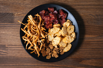 cheese with snacks and croutons on a black plate on a wooden background