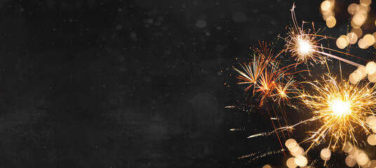 Silvester New Year 2024 background banner panorama long- firework and sparklers on dark black night...