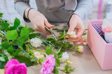 Obraz na płótnie Canvas Professional floral artist, florist holding cutter and cutting flower stems in bright room of flower shop, workshop - close up view. Floristry, handmade and small business concept