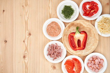 Slicing fresh food for pizza, with dough on a wooden background. Delicious homemade food. Top view with copy space.