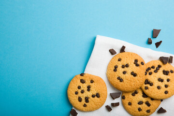 Delicious cookies with chocolate chips on a colored background