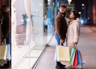 Happy black couple hugging and holding shopping bags