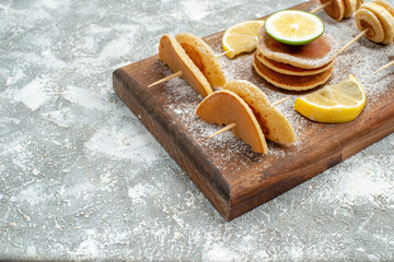 Half shot of buttermilk pancakes with lemons on wooden cutting board on blue background