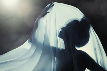 Sensual woman silhouette covered with transparent cloth. Mysterious night, touching the light with...