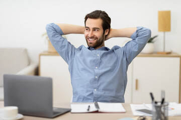 Carefree Businessman Relaxing Sitting Holding Hands Behind Head At Workplace