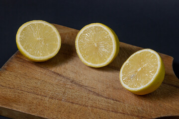 Lemons on a black background. Citrus fruit. Healthy food. Sliced lemons on a wooden board. Sour fruit