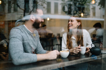 Cheerful young couple enjoying hot beverages in cafe