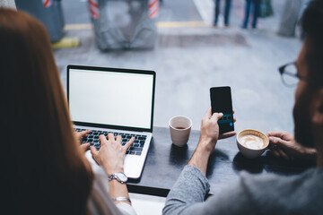 Man with smartphone and female worker typing on laptop