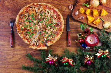 Christmas pizza.Pizza on a plate on a wooden table decorated with Christmas tree branches and decorations.