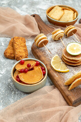 Easy pancakes with lemons on cutting board and cookies on orange towel on blue background image
