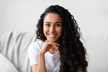 Fototapeta na wymiar Closeup portrait of dark-haired curly woman posing at home
