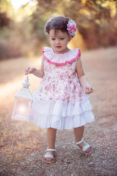 Ni&ntilde;a paseando por el campo en verano con farol iluminado