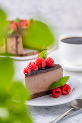 Chocolate cheesecake with fresh raspberries and mint leaves.