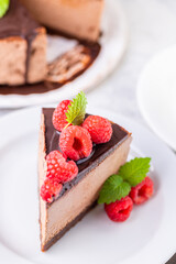 Chocolate cheesecake with fresh raspberries and mint leaves.