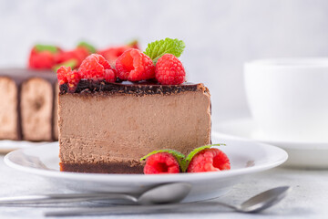 Chocolate cheesecake with fresh raspberries and mint leaves.