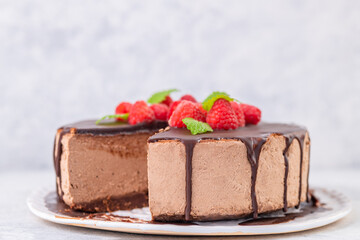 Chocolate cheesecake with fresh raspberries and mint leaves.