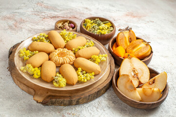 Naklejka na ściany i meble sideward photo of a plate of cookies on wooden platter and different dry flowers and fruits