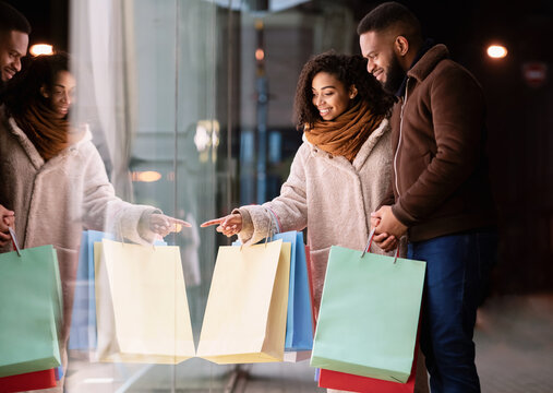 Happy Black Family With Shopping Bags Pointing At Mall Window